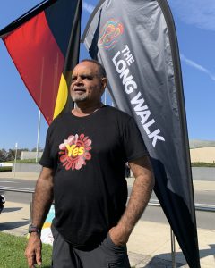 Man in front of aboriginal flag and the long walk flag